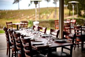 a long table and chairs in a restaurant with a view at RidgeView in Pokolbin