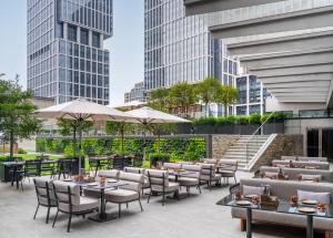 eine Terrasse mit Tischen, Stühlen und Gebäuden in der Unterkunft Jen Shenzhen Qianhai By Shangri-La in Shenzhen