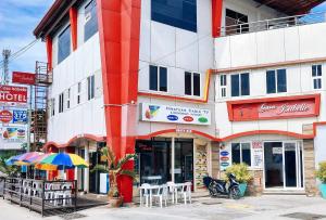 a red and white building with tables and an umbrella at RedDoorz @ Isabelle Tourist Hotel Hinatuan in Hinatuan