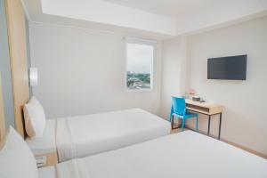 a hotel room with two beds and a desk and a tv at Hotel Citradream Bintaro in Serpong