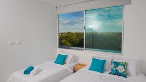 deux lits dans une chambre avec une grande fenêtre dans l'établissement Magico Apartamento Frente al Mar 4 Habitaciones PAZ345, à Coveñitas