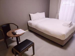 um quarto com uma cama, uma mesa e uma cadeira em Mr.KINJO 宮古島アパラギリゾートⅠ em Ilhas Miyako