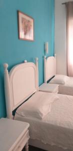 2 camas blancas en una habitación con paredes azules en Residencial Miradoiro Guest House, en Portimão