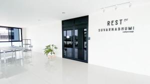 Habitación blanca con puerta negra y mesa en Rest Suvarnabhumi en Samutprakarn