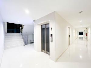 - un couloir blanc avec des sols et des escaliers blancs dans l'établissement Rest Suvarnabhumi, à Samutprakarn