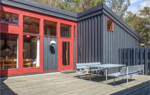 ein schwarzes winziges Haus mit einer Bank auf dem Deck in der Unterkunft Gorgeous Home In Nex With Wifi in Vester Sømarken