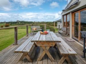 una terraza de madera con una mesa de picnic en una casa en Blue Wren Cottage Farm Stay, en Yanakie