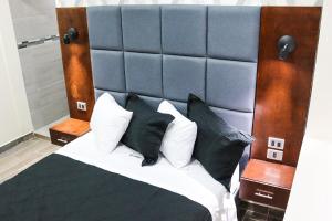HOTEL MISION 11 في تيخوانا: غرفة نوم بسرير كبير ومخدات بيضاء وسوداء