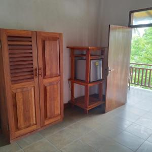 Habitación con TV, armario y puerta. en Beach House Habaraduwa, en Koggala