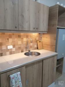 a kitchen counter with a sink and wooden cabinets at Los Soles Suite Mall del Sol Guayaquil Airport in Guayaquil