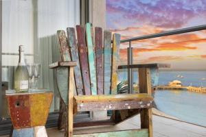 een houten stoel op een balkon met een fles wijn bij ZEN POINT PENTHOUSE 3-BR Executive W/front Retreat in Darwin