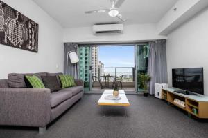 a living room with a couch and a tv at ZEN CITY & SEA Executive 1-BR Suite in Darwin CBD in Darwin