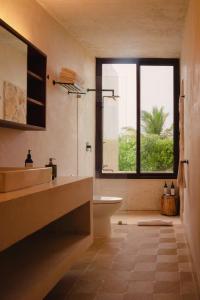 een badkamer met een wastafel, een bad en een raam bij Club de Patos in Sisal