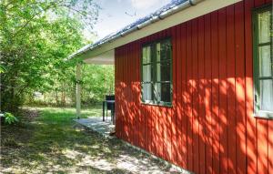 ein rotes Haus mit einem Fenster an der Seite in der Unterkunft Awesome Home In Aakirkeby With Kitchen in Vester Sømarken