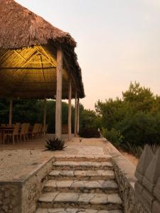 a building with a straw roof and some chairs and stairs at Club de Patos in Sisal