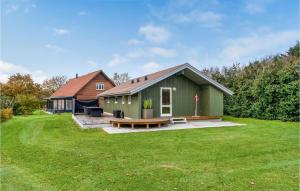 a green building with a picnic table in a yard at Nice Home In Gredstedbro With House A Panoramic View in Gredstedbro