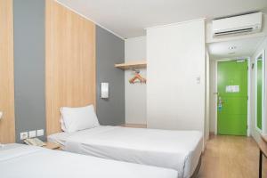 a bedroom with two beds and a green door at Hotel Citradream Bandung in Bandung