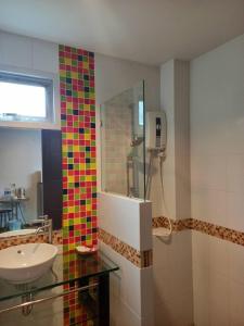 y baño con lavabo y ducha con azulejos de colores. en Benjamas Place, en Rawai Beach