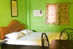 Maro Bianco's Inn Lubao Pampanga by RedDoorz في Lubao: غرفة نوم خضراء بسرير وطاولة ونافذة