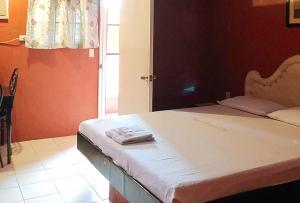 Maro Bianco's Inn Lubao Pampanga by RedDoorz في Lubao: غرفة نوم مع سرير وفوط مطوية عليه
