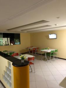 comedor con mesas y sillas y TV en Iapi Hotel, en Salvador