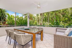 comedor con mesa de cristal y sillas en Oasis at Palm Cove, en Palm Cove