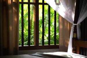 a bedroom with a window with a view of trees at Birds Paradise Cabanas Unawatuna in Unawatuna