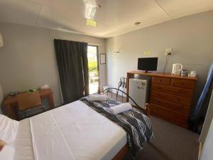 1 dormitorio con 1 cama y vestidor con TV en Coal n Cattle Hotel Motel, en Moura