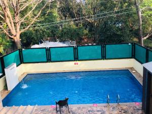 une piscine avec une clôture et un chien noir dans l'établissement Goa Junction by Daystar Ventures, à Anjuna