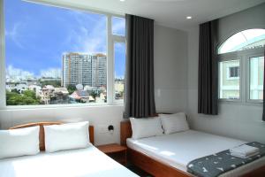 twee bedden in een kamer met een groot raam bij HOTEL NGUYEN ANH in Ho Chi Minh-stad