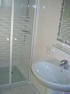 een witte badkamer met een douche en een wastafel bij Gite Le Mascaret in Roz-sur-Couesnon