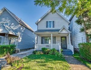 a white house with a porch and a driveway at Cozy Updated 3-BR apartment near Peace Bridge in Buffalo