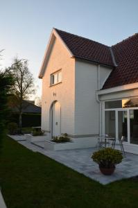 een huis met een witte deur en een patio bij Villa Grillons in Koksijde