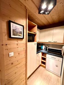 a kitchen with wooden walls and a refrigerator and a stove at VUE PANORAMIQUE & RÉNOVÉ CENTRE STATION 1800 - 2 Chambres - 6 PERS in Les Orres