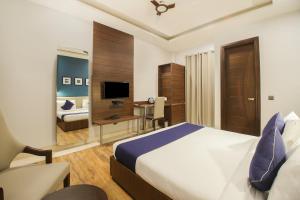 a bedroom with a bed and a desk and a television at SilverKey M&m Residency in New Delhi