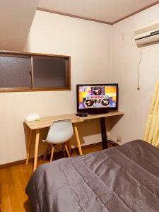 大泉学園ヴィラ في Katayama: غرفة نوم بها مكتب وبه جهاز كمبيوتر وسرير
