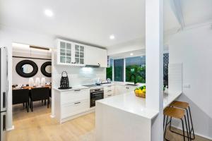 une cuisine avec des placards blancs et une salle à manger dans l'établissement 4 Bedroom Family Home with Pool - Uplands Drive - Q Stay, à Gold Coast