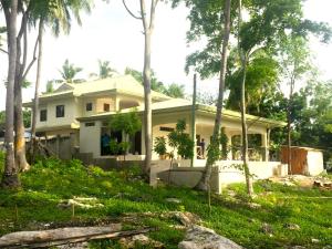 une maison blanche avec des arbres devant elle dans l'établissement Lambug Beach Homestay, à Lambug