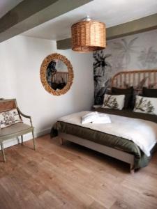 een slaapkamer met een bed, een spiegel en een stoel bij A l'Ombre de la Dame in Cucuron