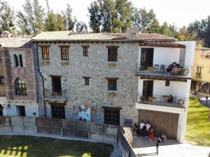 un antiguo edificio de piedra con gente de pie en el balcón en San Torino en Tlaxcala de Xicohténcatl