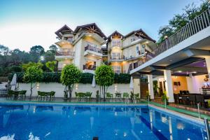a hotel with a swimming pool in front of a building at Regenta Resort Exotica Dharamshala on Hilltop in Dharamshala