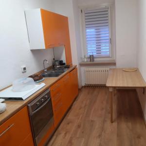 a kitchen with orange cabinets and a wooden table at Appartamento vista Parco Adamello Brenta in Ossana