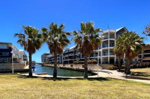 a hotel with palm trees in front of a body of water at DelMar 3 in Mandurah
