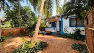 eine Palme vor einem blauen und weißen Haus in der Unterkunft Coco inn Goa in Candolim