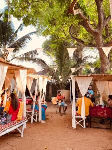 坎多林的住宿－Coco inn Goa，一群人坐在帐篷下的椅子上