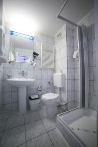 a bathroom with a sink and a toilet and a tub at Hotel Alexandros Busteni in Buşteni
