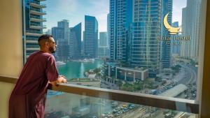 a man standing on a balcony looking out at the city at Lunar Hostel Plus in Dubai