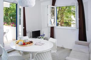 ein weißes Esszimmer mit einem weißen Tisch und einem Fenster in der Unterkunft Apartments Aminess Port 9 Residence Korcula - CIN1000d-CYB in Korčula