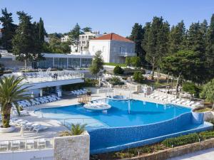 een uitzicht over een zwembad met stoelen en een gebouw bij Apartments Aminess Port 9 Residence Korcula - CIN1000d-CYB in Korčula