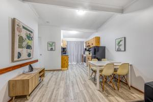 a living room with a table and chairs and a kitchen at Beachcomber Peregian Beach in Peregian Beach